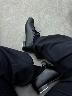 a pair of black shoes and pants sitting next to each other on top of a floor