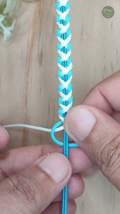 two hands are working on a blue and white crochet hook with yarn in it