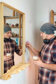 two men standing in front of a mirror holding candles