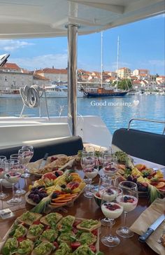 a wooden table topped with lots of food on top of a boat next to the ocean