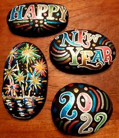 three rocks decorated with fireworks and the words happy new year painted on them are sitting on a table