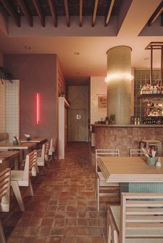 the interior of a restaurant with wooden tables and white chairs, tiled walls and floor