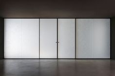 an empty room with white walls and sliding glass doors on the door, in front of a black wall