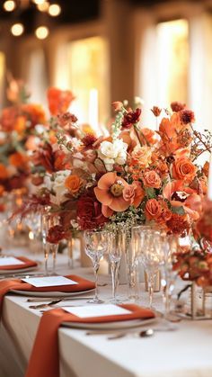 a long table with orange and white flowers in vases on top of each other