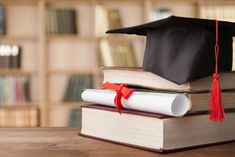 a stack of books with a graduation cap and tassel sitting on top of them