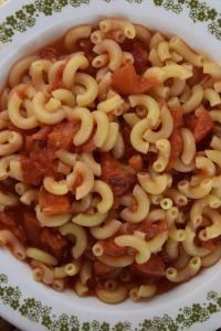 a white bowl filled with pasta and sauce on top of a green and white plate