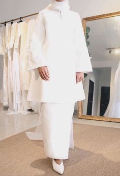 a woman standing in front of a mirror wearing a white outfit