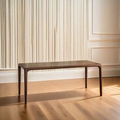 a wooden table sitting on top of a hard wood floor next to a white wall