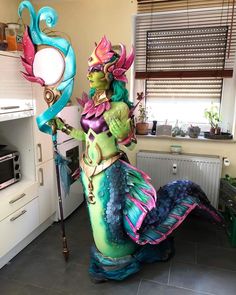 a woman dressed as a mermaid holding a wand in her hand and standing next to a stove