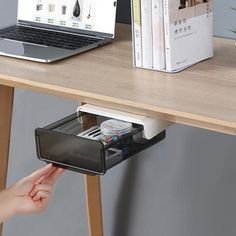 a desk with a laptop and other office supplies on it, including a drawer for pens