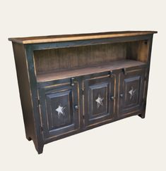 an old fashioned wooden cabinet with metal stars on the doors and bottom drawer is shown