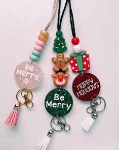 several christmas themed key chains are hanging on a white surface with the words be merry