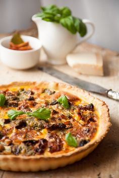 a pizza sitting on top of a wooden cutting board next to a knife and bowl