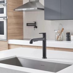 a kitchen sink with a black faucet next to an oven and counter top