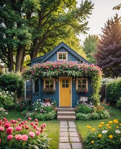 a small blue house surrounded by flowers and trees