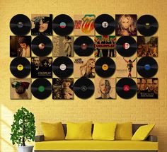 a living room filled with lots of vinyl records on the wall next to a couch