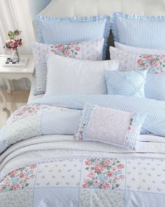 a bed with blue and white bedspread, pillows and flowers on the comforter