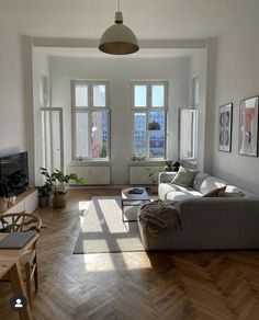 a living room filled with furniture and windows next to a wooden floor covered in hard wood