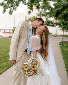 a bride and groom kissing on the sidewalk