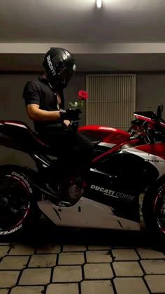 a man sitting on top of a motorcycle with a flower in his hand and wearing a helmet