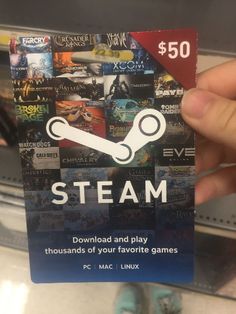 a person holding up a card with steam on it in front of some video games