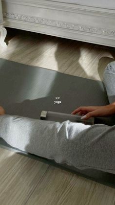 a person sitting on a yoga mat with their feet up in the air and using a laptop