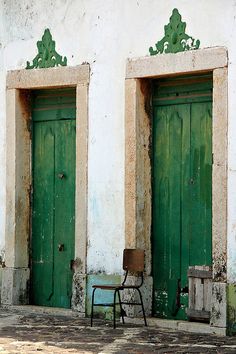 two green doors and a chair in front of them