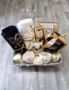 a gift basket filled with coffee, tea cups and personalized items on a wooden floor