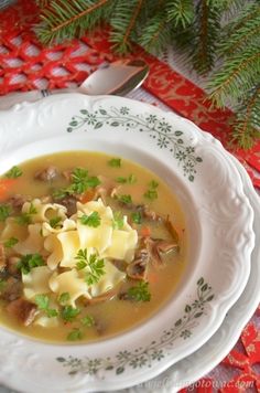 a white bowl filled with pasta and meat soup on top of a red table cloth