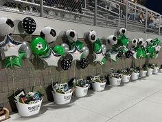 a wall with soccer balls and balloons on it, along with buckets filled with gifts