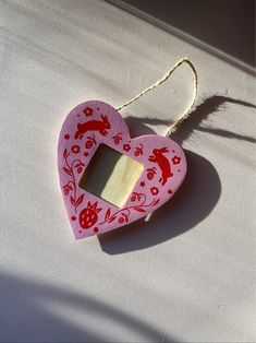 a pink heart shaped ornament hanging from a string on a white tablecloth