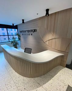 an office with a curved reception desk in front of a large window, and a plant on the counter