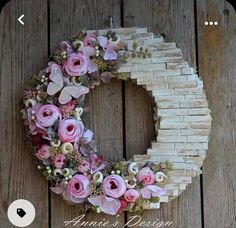 a wreath made out of wood with pink flowers and butterflies on the letter o in front of a wooden wall