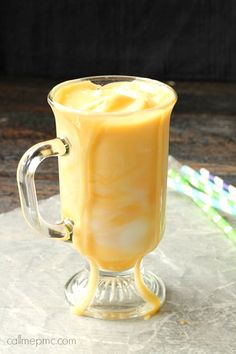 a glass mug filled with liquid sitting on top of a table next to a straw