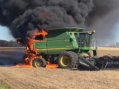 a large green tractor with flames coming out of it's tires in the middle of a field