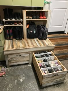 an open drawer with shoes and backpacks in it next to a wooden bench on the floor