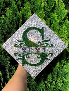 someone is holding up a graduation cap with the letter q on it in front of some bushes