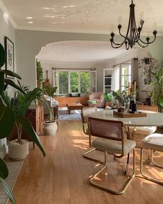 a living room filled with furniture and a chandelier hanging from the ceiling over a wooden floor