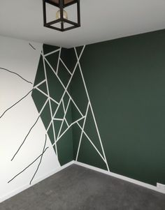 an empty room painted with green and white lines on the wall, next to a light fixture