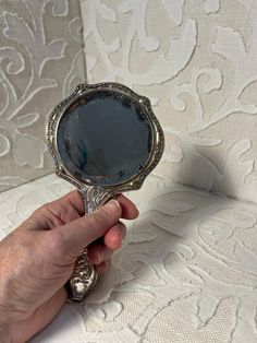 a person holding a mirror in their hand on top of a white fabric covered couch