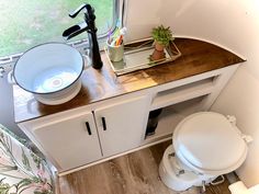 a bathroom with a toilet, sink and mirror in it's corner next to a window