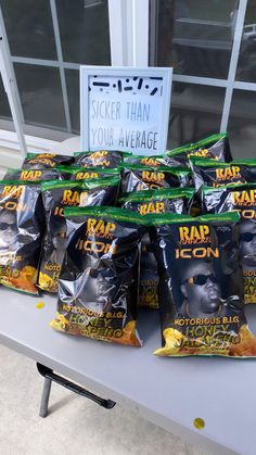 bags of rap icons sit on a table in front of a sign