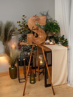 a wooden sign sitting on top of a table next to candles and potted plants