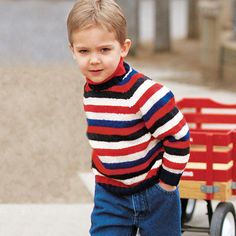 a little boy standing next to a red wagon