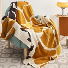 an orange and white blanket sitting on top of a blue chair next to a lamp