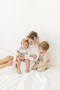 three children are sitting on the bed with their arms around each other as they look at something