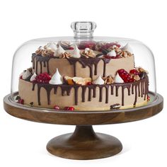 a cake under a glass dome with chocolate icing and toppings on the top