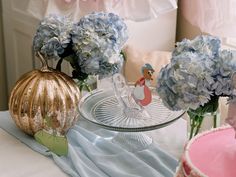 blue hydrangeas in vases on a table with a glass plate and other decorations