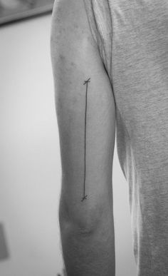 a man's arm with an arrow tattoo on the left side of his arm