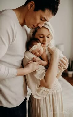 a man and woman holding a baby in their arms